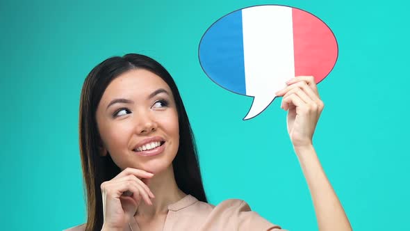 Dreaming Pretty Female Holding French Speech Bubble, Fluent Foreign Language