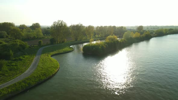 Aerial view in the sunset going over a river revealing the village of Clairmarais, France in the dis