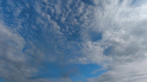 Time lapse. Blue sky and clouds drifting in different directions.