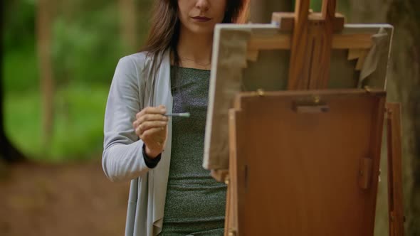 Portrait of a Beautiful Brunette Woman Painting a Picture on Canvas in a Park.