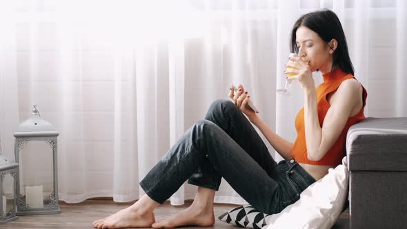 Young Woman Sitting on the Flor with Orange Juice