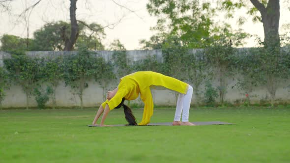 Wheel Yoga pose or Chakrasana is being done by an Indian woman in a park