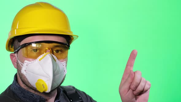 Male Builder in Respirator and Goggles on Green Background with Colored Key