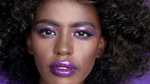 Close Up Portrait of Beautiful African Female Model with Afro Hair and Glowing Purple Makeup