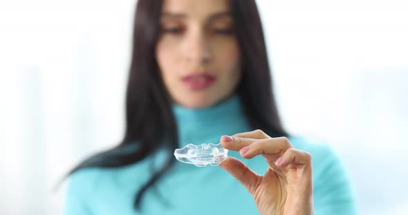 Young Woman Holds Plastic Transparent Mouth Guard in Hands