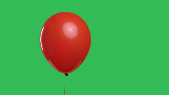 Red Oval Shaped Balloon Hanging in the Air Against the Background of a Green Screen Chroma Key