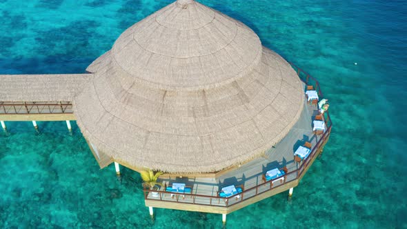 Aerial top view on water bungalow with leaf roof and young couple in Maldives resort island