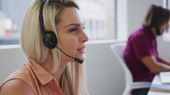 Caucasian business people wearing headphones talking to customers in modern office