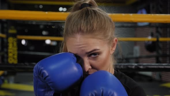 Closeup of a Female Boxer in Blue Boxing Gloves Practicing a Punch in the Gym