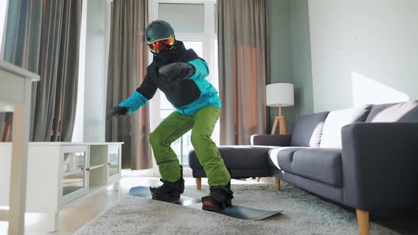 Fun Video. Man Dressed As a Snowboarder Rides a Snowboard on a Carpet in a Cozy Room. Waiting