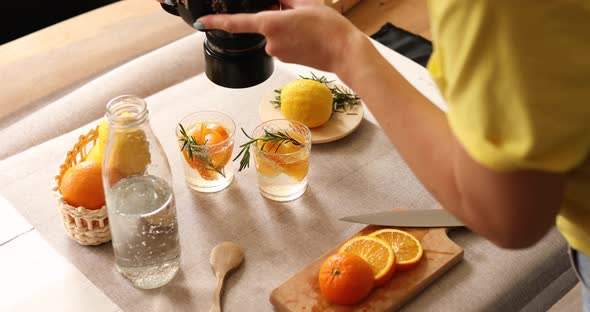 Woman food photographer take pictures with camera of fresh summer citrus lemonade drink