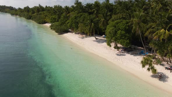 Drone flight over the sandy coast of the Maldives. On one side, great water. On the other hand, gree