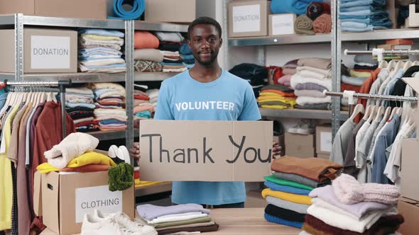 Portrait View of the Diverse Male Volunteer Holding Cupboard Banner with Thank you Phrase and