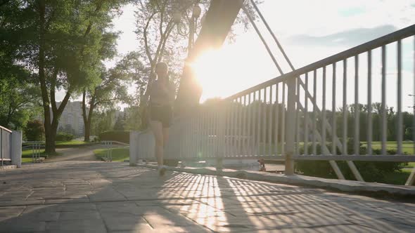 Asian Young Beautiful Woman Running for Health in the Evening Sunset on the Bridge in Public Park