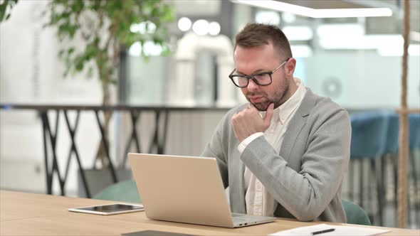 Pensive Creative Man Thinking and Working on Laptop