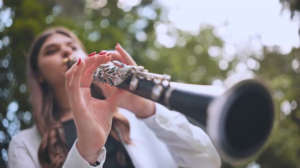 A Girl Plays the Clarinet in the Park in the Summer