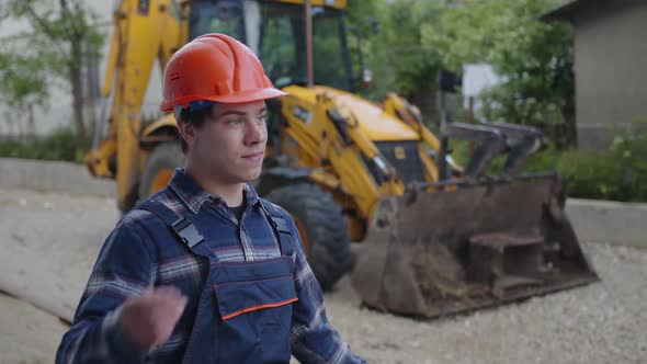 Man Stands and Takes Off His Orange Helmet