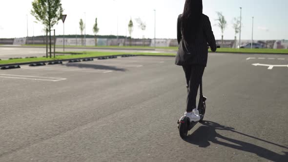 Business Woman Riding Electric Scooter at Parking Lot Follow Shot