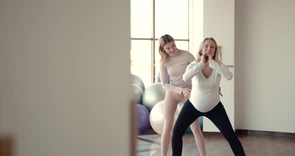 Pregnant Woman and Her Personal Trainer Doing Stretching Exercises