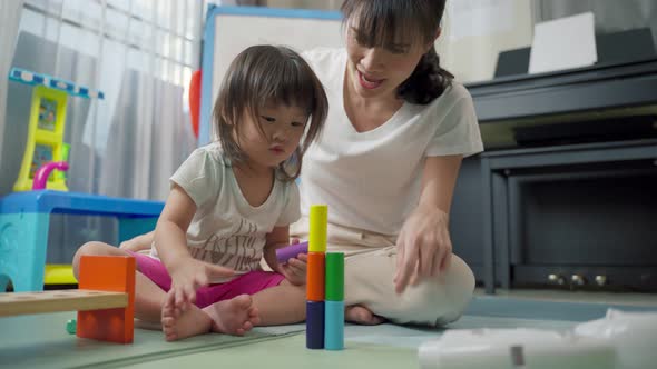 Asian happy family, beautiful mother and little girl kid playing toy together in living room at home