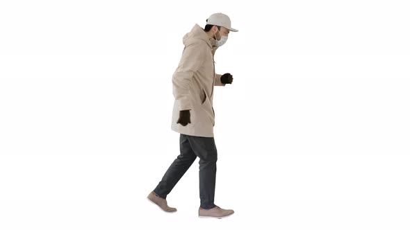 Young Man in Outdoor Clothes and Medical Mask Jogging on White Background
