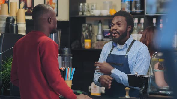 Black Man Stands Behind Bar Counter and Talks