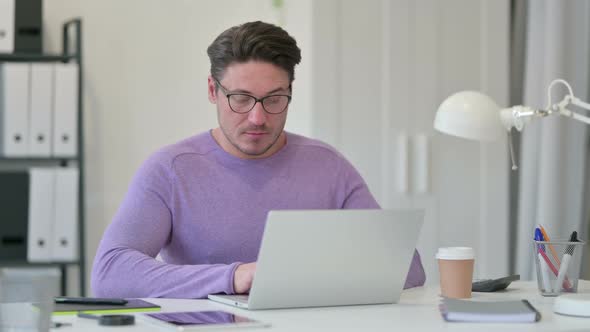 Middle Aged Man Having Loss on Laptop in Office 