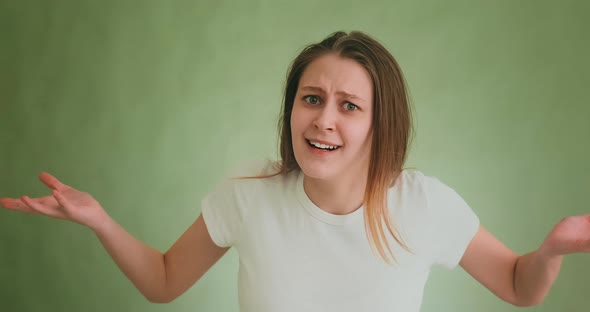 Disappointed Angry Woman Shrugs Posing for Camera on Green