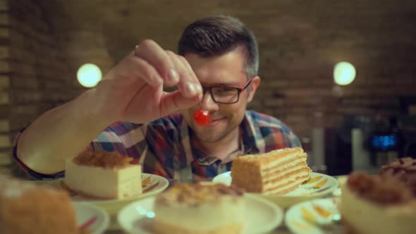 A Male Baker is Decorating Cake with Cherry on Kitchen