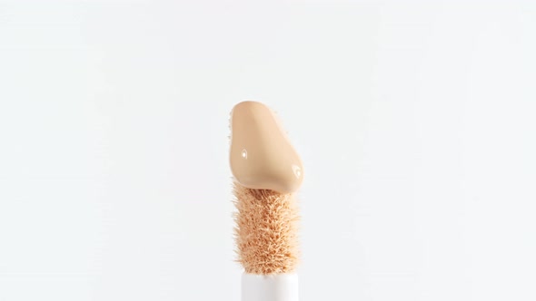 Makeup Liquid Beige Foundation Pouring on Makeup Brush Closeup