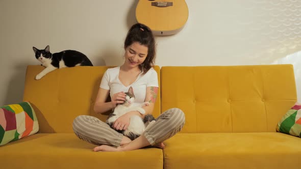 Young Pretty Woman Sitting on Coach at Home with Her Cats