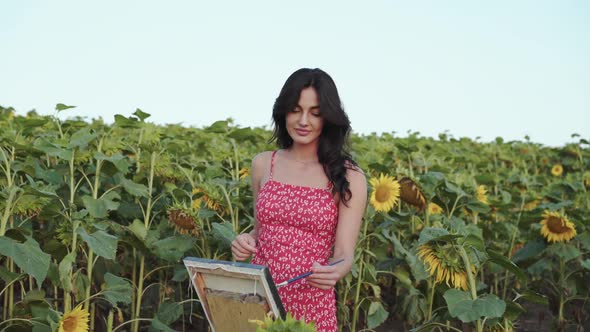 Pretty Female Artist in Dress Paints a Landscape Among Sunflowers