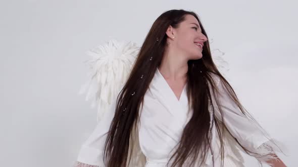 Brunette Girl with Angel Wings Dancing on a White Background