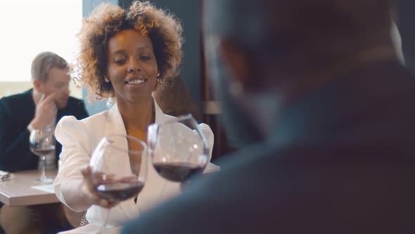 Back View of African Man Celebrating Anniversary with Girlfriend Clinging Glasses with Red Wine in