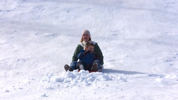 Mother and son riding sled, slow motion