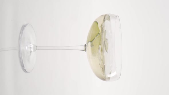 Vertical video, Close-up: cucumber fells in a glass of bubbling champagne