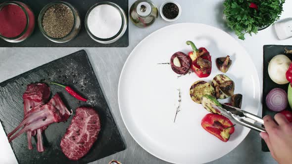 Chef plating a big piece of meat with some vegetables as side dish, close up view from above.