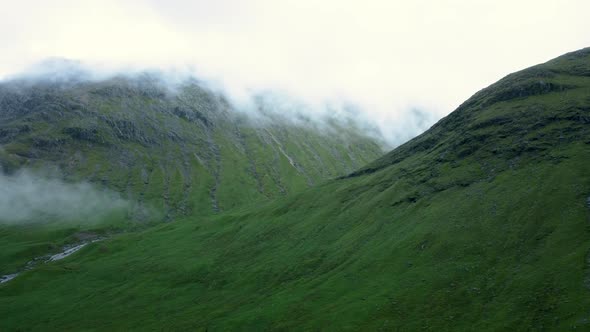 Panning drone shot of the clouds flow through mountain peak