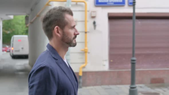 Close Up of Mature Adult Man Walking in Empty Street Side View