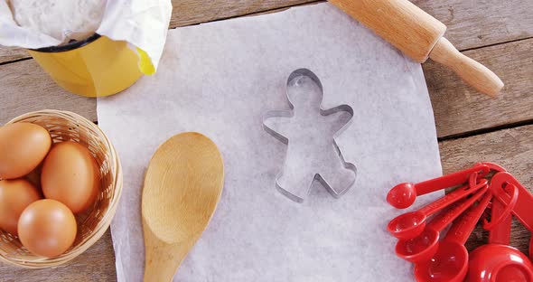 Butter paper, flour, rolling pin cookie cutter and eggs kept over a wooden table 4k