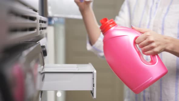 Closeup of a Woman's Hand Pouring Washing Powder Into a Washing Machine in a Public Laundry