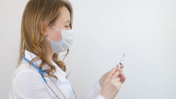 A doctor around his neck holds a medical syringe in his hands before an injection