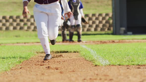 Low section of female baseball players playing on the field, hitter running for base