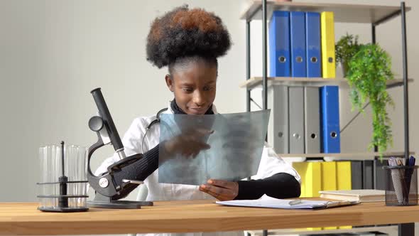 African American Female Doctor Working with the Xray at Desk