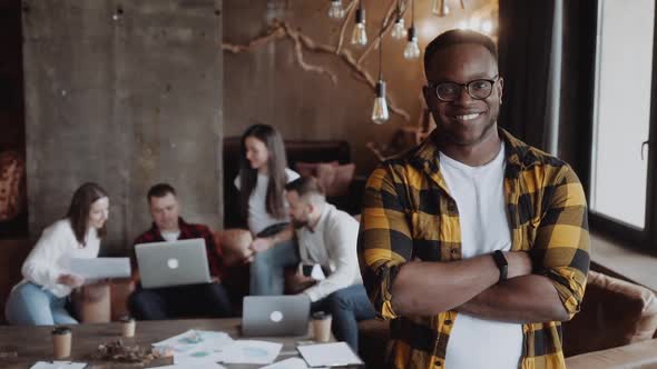 Portrait of Successful Black Guy Looking at the Camera at His Work Place in the Office in Casual