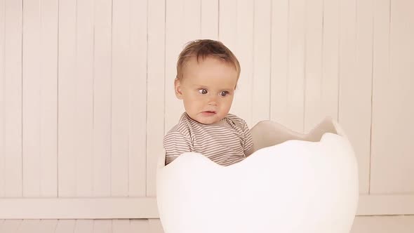 A Small Child Is Sitting in a Toy Egg Shell.