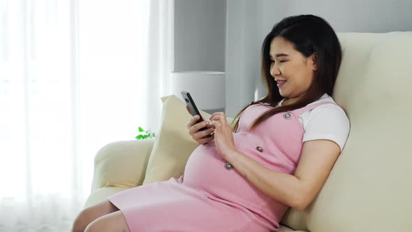 pregnant woman using smartphone on sofa in the living room