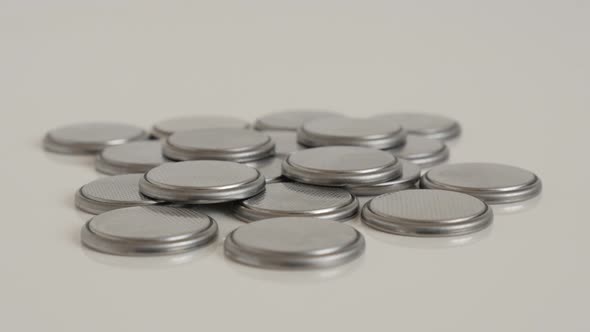 Pile of watch batteries on white 4K tilting video alt