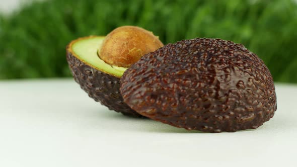 Avocado rotates on a green grass background. 4K video close-up of wholesome and healthy food.