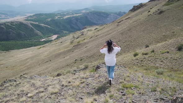 Attractive Brunette in a Hat and White Shirt Is Enjoying Nature in the Mountains. Beautiful Young